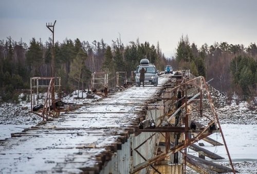 Vitim daryosining tepasiga qurilgan Kuandiya ko'priga, Sibir. Boshqa yo'l yo'q shuning uchun haydovchilar bu havfli ko'prik ustidan o'tishlariga majbur.