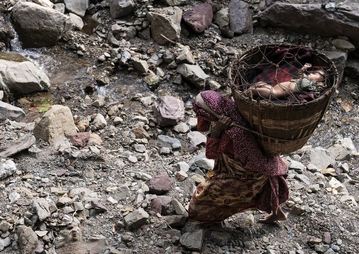 10. Nepallik ko‘chmanchi ayol savatida uhlayotgan farzandini ko‘tarib ketyapti