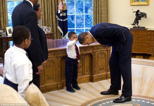 Obama, Oq uyning xizmatchilaridan birining o’g’li uning boshiga qo’li yetishi uchun, engashgan. 2009 yil 8 may.